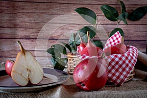 A red pear cut in half and other juicy red battler pears in a basket. Organic and natural products. Normal View