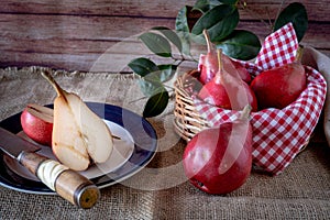 A red pear cut in half on a plate and other juicy red battler pears in a basket. Organic and natural products. Healthy food. High