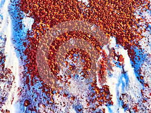 Red pebbles or rubberized textured material and white snow on it. Background, texture, frame, copy space. Contrast of