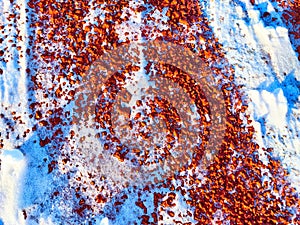 Red pebbles or rubberized textured material and white snow on it. Background, texture, frame, copy space. Contrast of