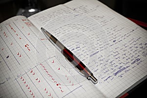 Red pen and writing pad with written lyrics, rhyming verses