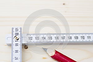 Red pencil and folding ruler lying on wooden board