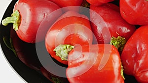 Red pepper on a black plate.Bell peppers whole with a green twig.