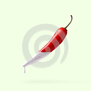 Red pepper with dripping white paint on light green background. Creative food concept