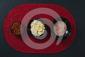 Red pepper flakes, roasted coconut chips and salt on aplace mat