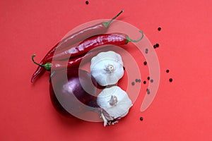 Red pepper, garlic and red onion lie on a red background