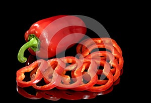 Red pepper on a glass table, is isolated on a black background