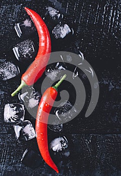 Red pepper and ice on a black wood background, fresh hot food on vintage table, freeze cold cube ice, mock up top