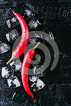 Red pepper ice on a black wood background, fresh hot food on vintage table, freeze cold cube ice, mock up top view