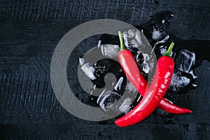 Red pepper and ice on a black wood background, fresh hot food on vintage table, freeze cold cube ice, mock up top view