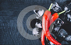 Red pepper and ice on black wood background, fresh hot food on vintage table, freeze cold cube ice, mock up top view