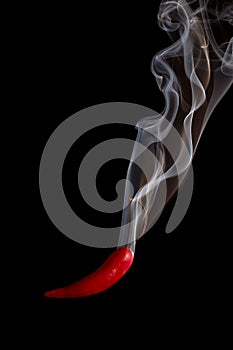 Red pepper pouring smoke on black background