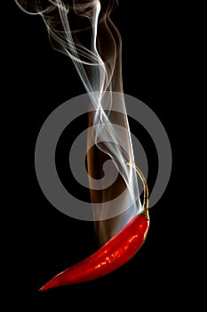 Red pepper pouring smoke on black background