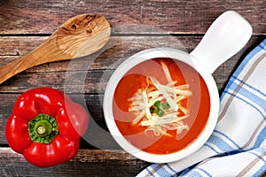 Red pepper soup overhead scene on rustic wood background