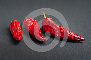 Red pepper. Three red dry peppers stacked on a black slate stone. Hot chili peppers