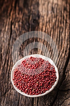 Red peppercorn in bowl on oak table