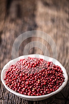 Red peppercorn in bowl on oak table