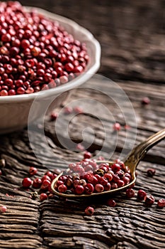 Red peppercorn in bowl and spoon on oak table