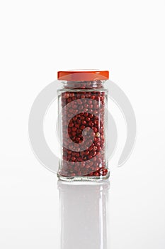 Red peppercorn in glass jar on white background