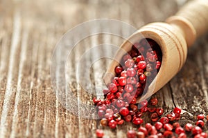 Red peppercorns in a spoon on wooden table.