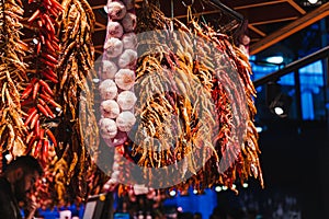 Red peppers, orange peppers, yellow peppers and garlic, hanged in the market