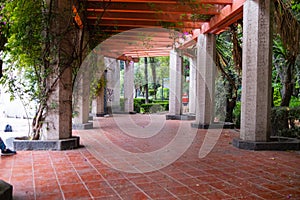 Red pergola and green leaves above corridor in park