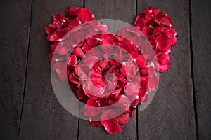 Red petal roses shaped like a heart on wood background,