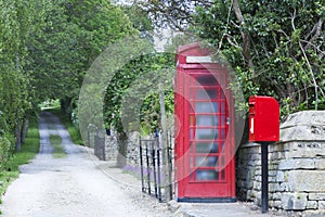 Red phone booth and postal box on a rural road