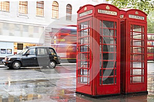 Red Phone cabines in London and vintage taxi.Rainy day.