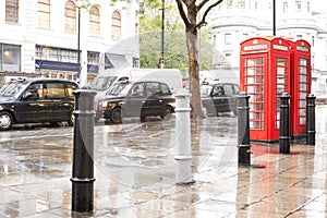 Red Phone cabines in London and vintage taxi.Rainy day.