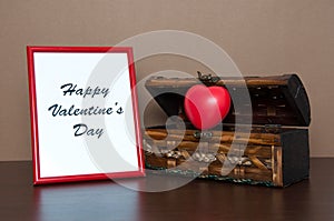 Red photo frame and opened decorative chest with heart on wooden table