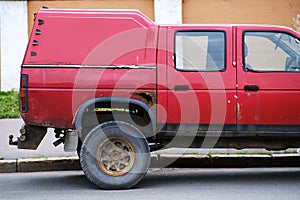Red Pick-Up Truck With Visible Rust and Damage Parked on a City Street