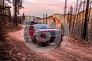 Red pickup with overland offroad equipment on rough dirt road in southern Utah desert