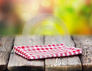 Red picnic cloth on wooden table mature bokeh background.