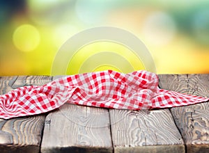 Red picnic cloth on wooden table mature bokeh background.