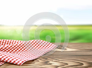 Red picnic cloth on wooden table nature background