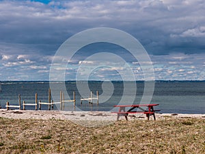 Red picnic table on a sandy beach