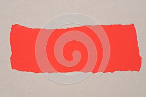 Red piece of torn paper on gray background texture