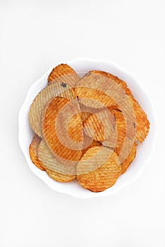 Red pieces of fried potatoes in a plate. Peppery chips on a white background