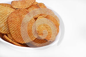 Red pieces of fried potatoes in a plate. Peppery chips on a white background