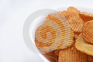 Red pieces of fried potatoes in a plate. Peppery chips on a white background