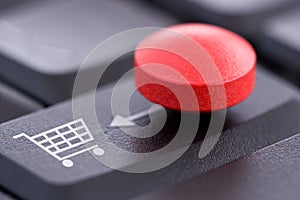 Red Pill and Shopping Cart on Computer Keyboard photo