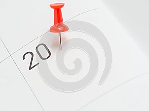 Red pin on 20 date on calendar paper