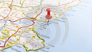 A red pin stuck in Carnoustie on a map of Scotland photo