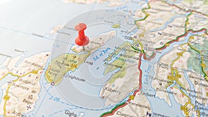 A red pin stuck in the island of Jura on a map of Scotland