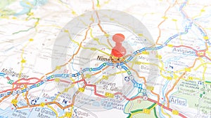 A red pin stuck in Nimes on a map of France photo
