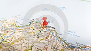 A red pin stuck in Palermo Sicily on a map of Italy