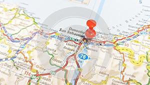 A red pin stuck in San Sebastian on a map of Spain