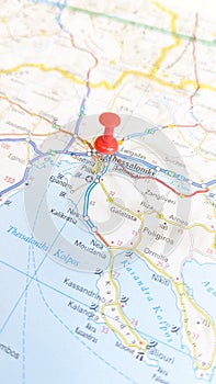 A red pin stuck in Thessaloniki on a map of Greece portrait photo