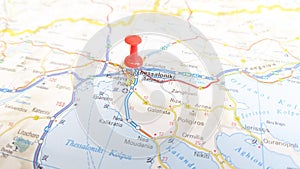 A red pin stuck in Thessaloniki on a map of Greece photo